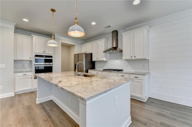 2090 Harvester Ln, Buford, GA 30518 - kitchen featuring wall chimney range hood, appliances with stainless steel finishes, an island with sink, light wood-style floors, and backsplash
