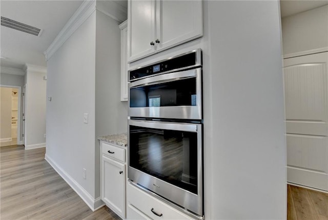 2090 Harvester Ln, Buford, GA 30518 - kitchen with double oven, ornamental molding, light wood-type flooring, white cabinetry, and light stone counters