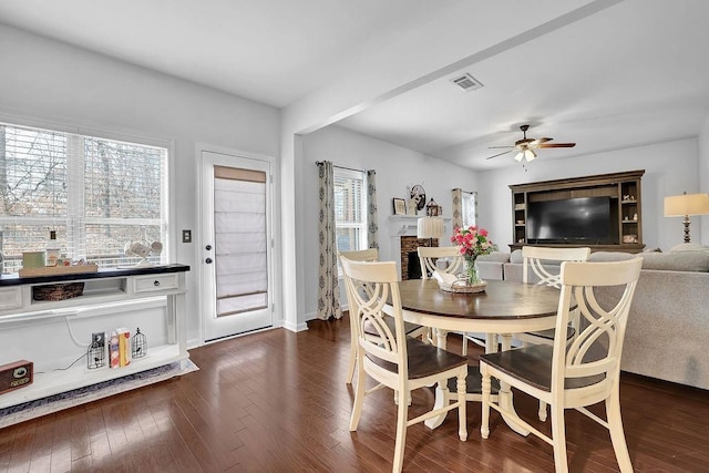 dining space featuring a brick fireplace, dark hardwood / wood-style floors, and ceiling fan