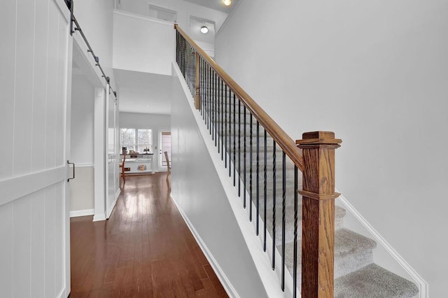 staircase with hardwood / wood-style floors and a barn door