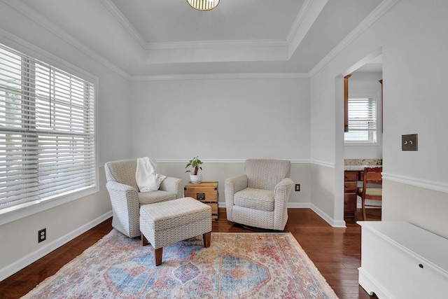 sitting room with dark wood-type flooring, a healthy amount of sunlight, and a tray ceiling