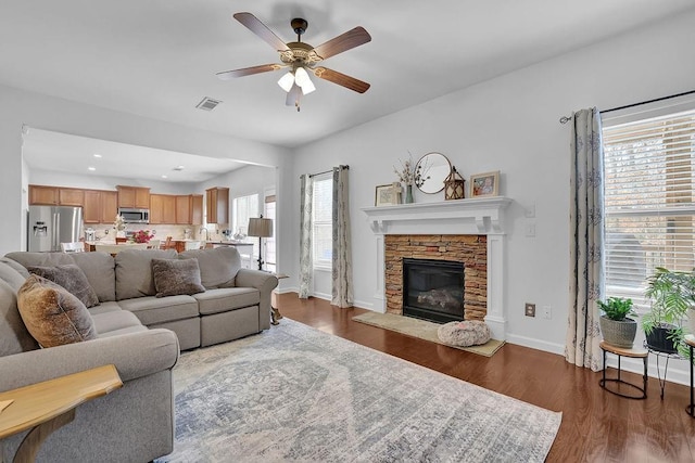 living room with plenty of natural light, dark wood-type flooring, a fireplace, and ceiling fan