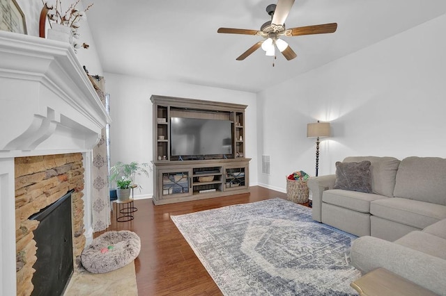 living room featuring ceiling fan, a fireplace, and dark hardwood / wood-style flooring