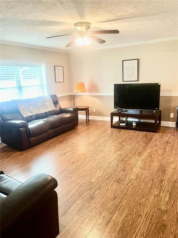 4567 Duncan Dr, Sugar Hill, GA 30518 - living area with a textured ceiling, wood finished floors, ceiling fan, ornamental molding, and baseboards