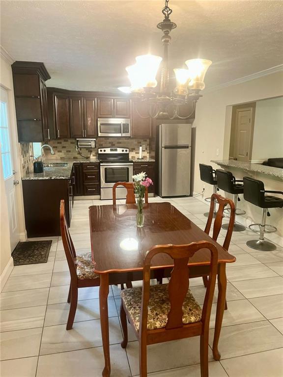 4567 Duncan Dr, Sugar Hill, GA 30518 - dining area featuring crown molding, light tile patterned floors, a chandelier, and a textured ceiling