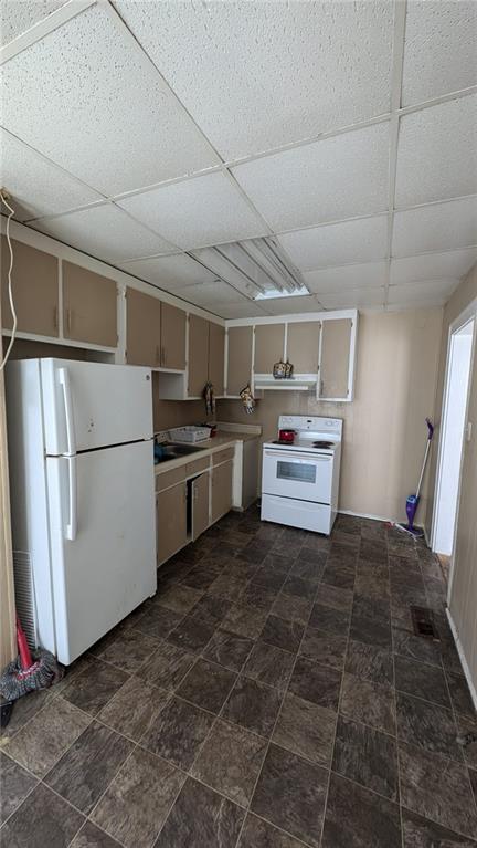 kitchen featuring a drop ceiling and white appliances