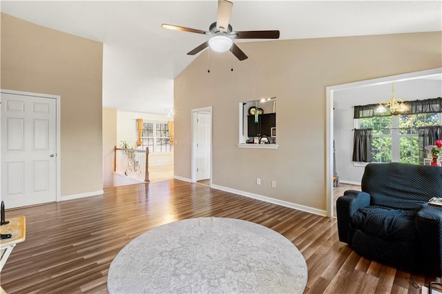 living room featuring ceiling fan with notable chandelier, hardwood / wood-style floors, and lofted ceiling