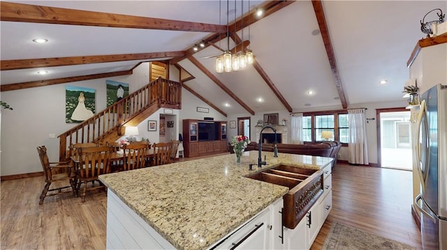 kitchen featuring light wood-style flooring, open floor plan, freestanding refrigerator, a fireplace, and beam ceiling