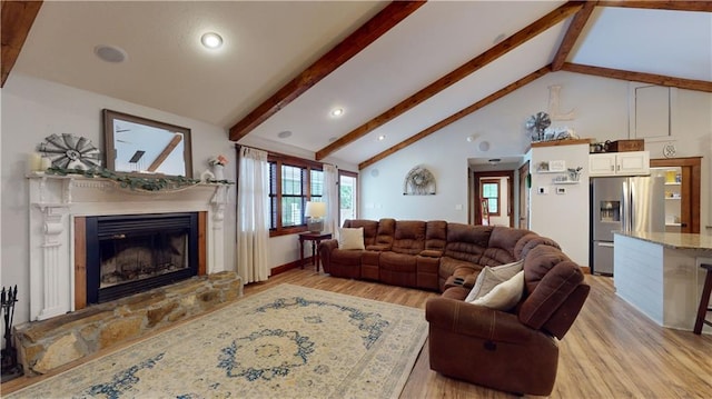 living room with high vaulted ceiling, light wood finished floors, a glass covered fireplace, and beam ceiling