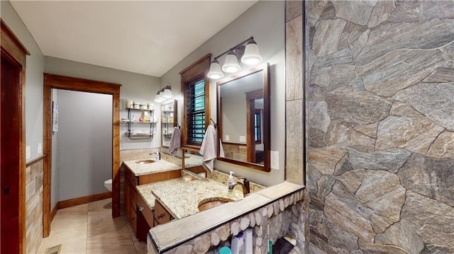 bathroom featuring toilet, two vanities, and a sink