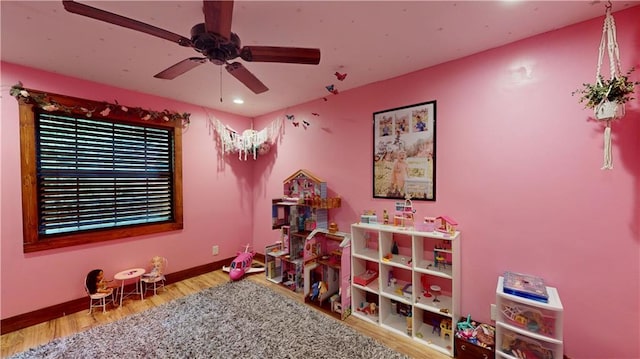 rec room with a ceiling fan, baseboards, and wood finished floors