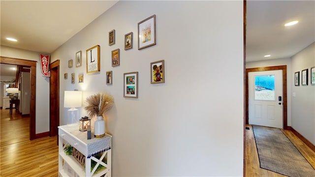 hall with light wood-type flooring, baseboards, and recessed lighting