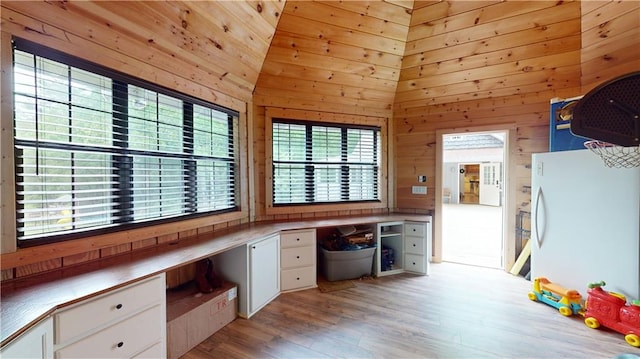 unfurnished office featuring light wood-type flooring, wooden walls, and a high ceiling