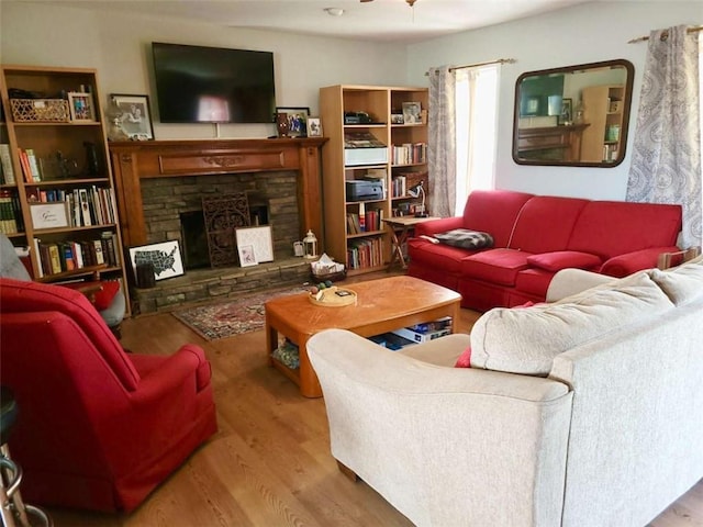 living area featuring a stone fireplace and wood finished floors