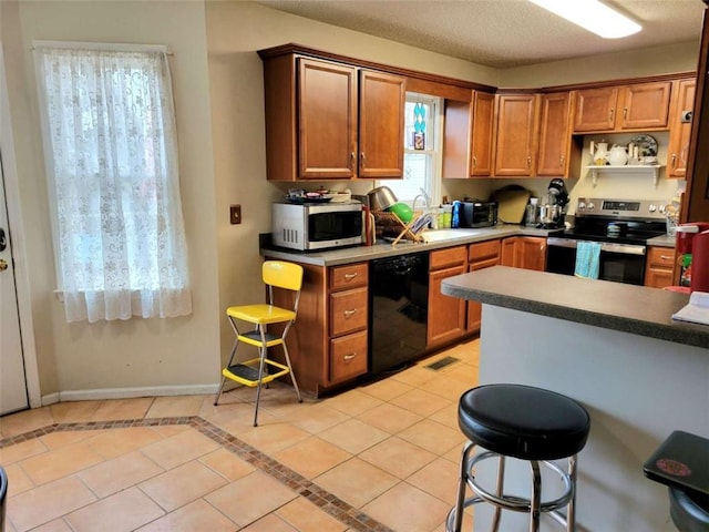 kitchen with light tile patterned floors, visible vents, baseboards, a sink, and appliances with stainless steel finishes