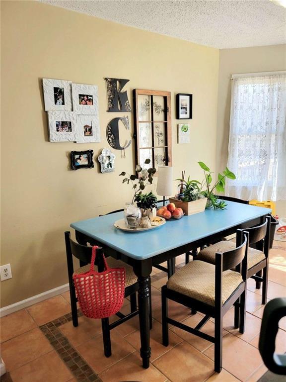 dining area with light tile patterned floors, baseboards, and a textured ceiling