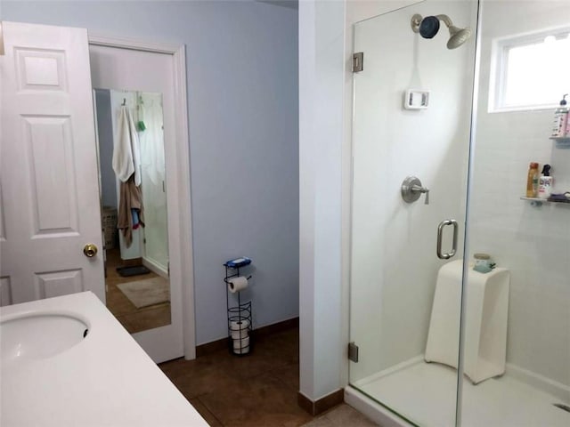 bathroom with a shower stall, baseboards, tile patterned floors, and a sink