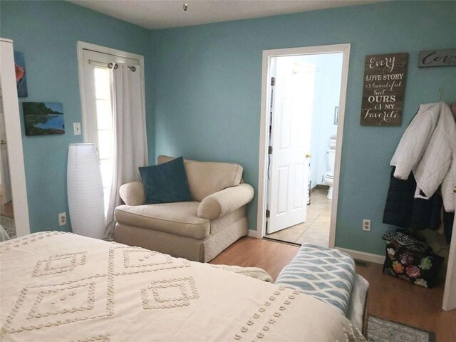 bedroom featuring baseboards, wood finished floors, and ensuite bathroom