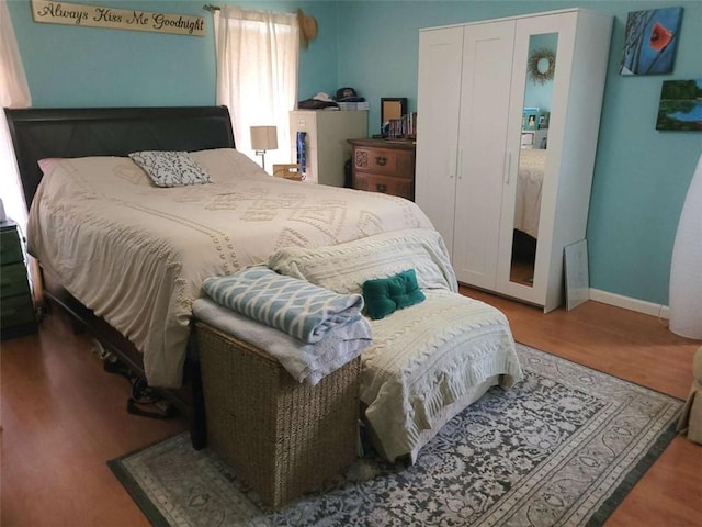 bedroom with a closet, baseboards, and wood finished floors