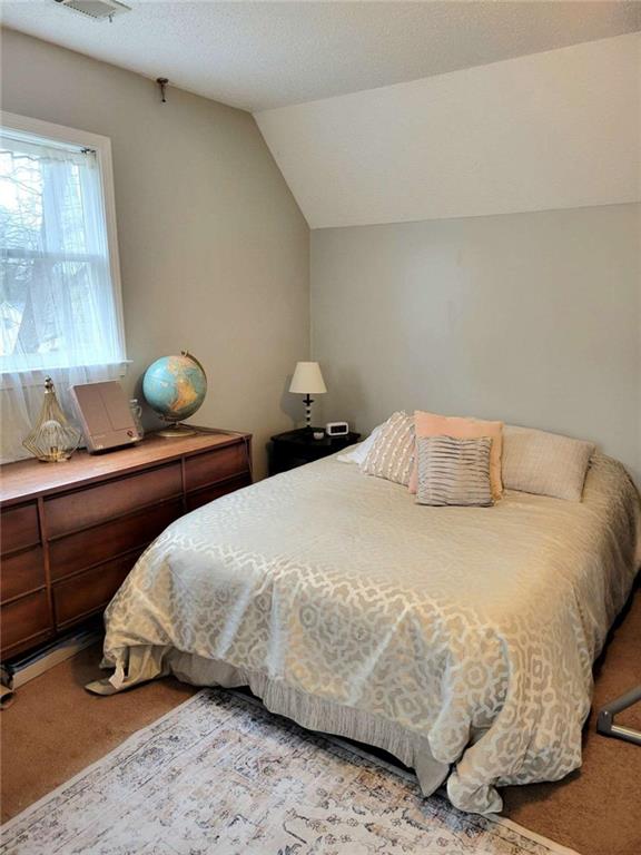 carpeted bedroom featuring lofted ceiling and a textured ceiling