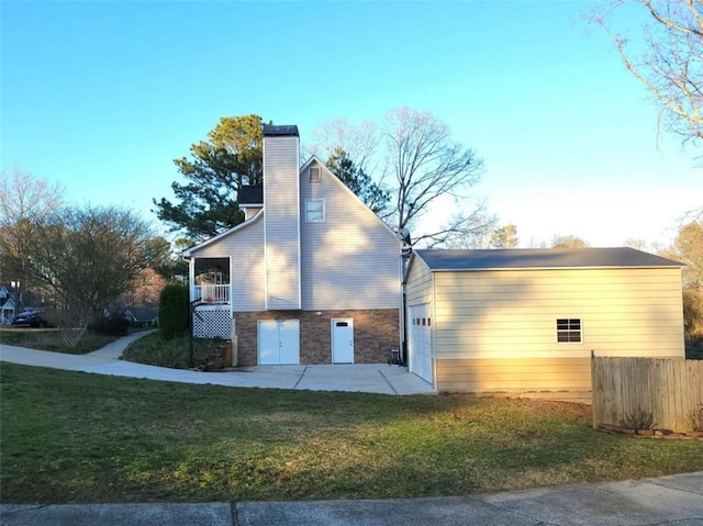 view of property exterior featuring a lawn, a chimney, a garage, an outbuilding, and stone siding