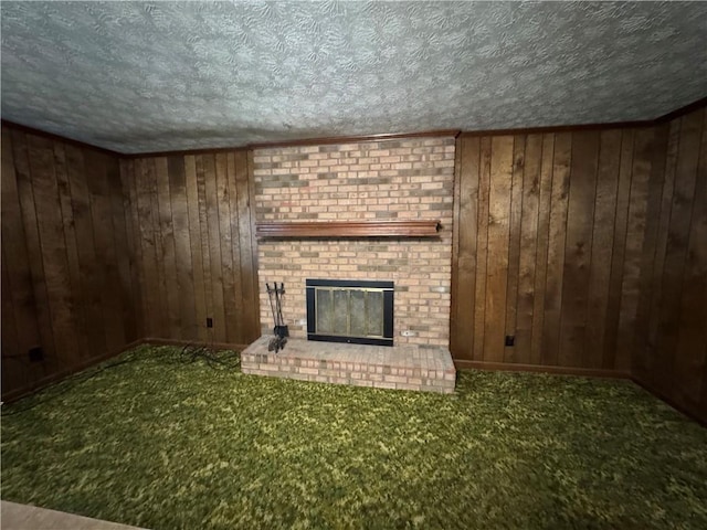 unfurnished living room with a textured ceiling, wood walls, carpet, and a fireplace