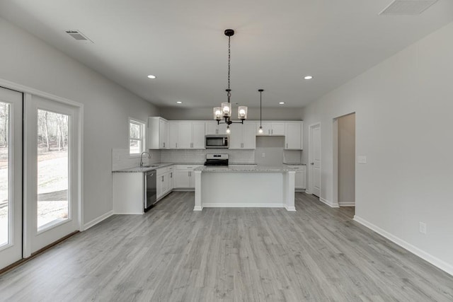 kitchen featuring appliances with stainless steel finishes, visible vents, light wood-style floors, and backsplash