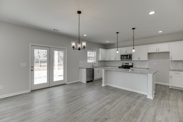 kitchen featuring stainless steel appliances, tasteful backsplash, light wood-type flooring, and white cabinets