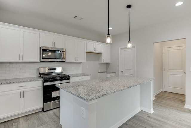 kitchen featuring light stone counters, stainless steel appliances, white cabinetry, light wood finished floors, and tasteful backsplash