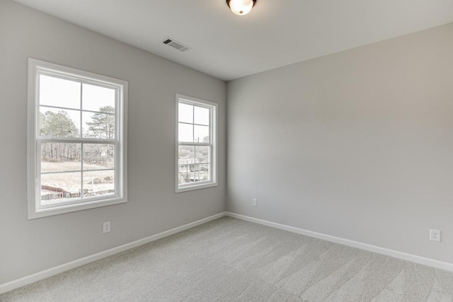 carpeted spare room with visible vents, plenty of natural light, and baseboards