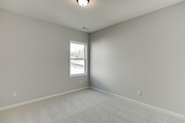 spare room with baseboards, visible vents, and light colored carpet