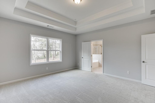 unfurnished bedroom with carpet floors, a tray ceiling, and visible vents