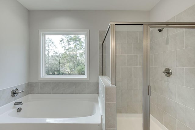 bathroom featuring a shower stall and a bath