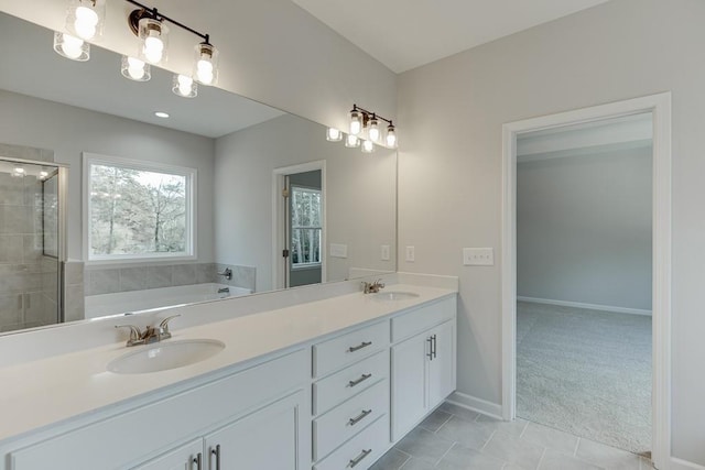 full bath with a bath, a stall shower, double vanity, and a sink