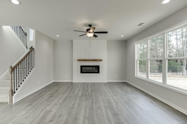 unfurnished living room featuring stairs, visible vents, a fireplace, and wood finished floors