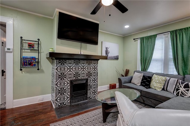 living room with a tile fireplace, hardwood / wood-style flooring, ceiling fan, and crown molding