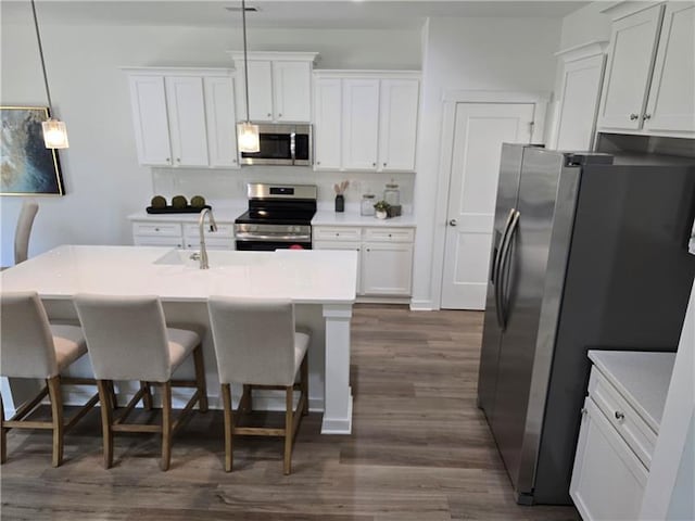 kitchen with pendant lighting, sink, appliances with stainless steel finishes, white cabinetry, and a kitchen breakfast bar