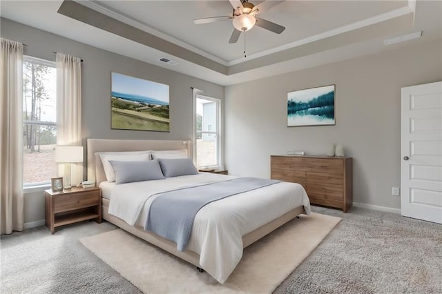 bedroom with ceiling fan, ornamental molding, a tray ceiling, and carpet floors