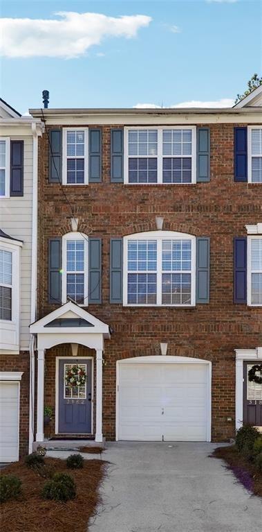multi unit property with driveway, brick siding, and a garage