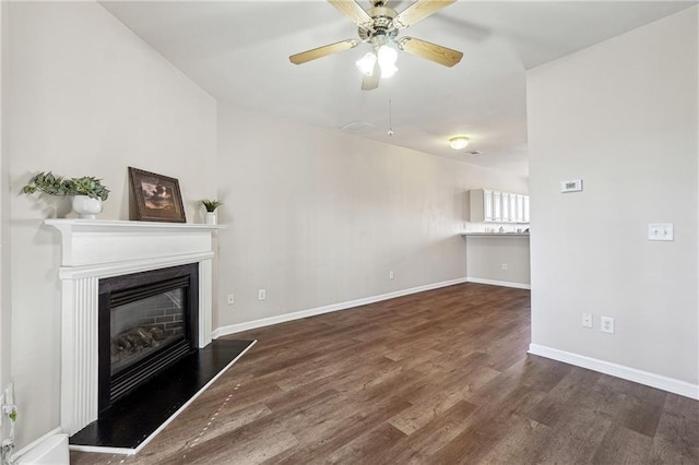 unfurnished living room with a ceiling fan, a glass covered fireplace, baseboards, and wood finished floors