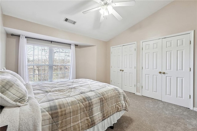 bedroom with visible vents, two closets, carpet, a ceiling fan, and vaulted ceiling