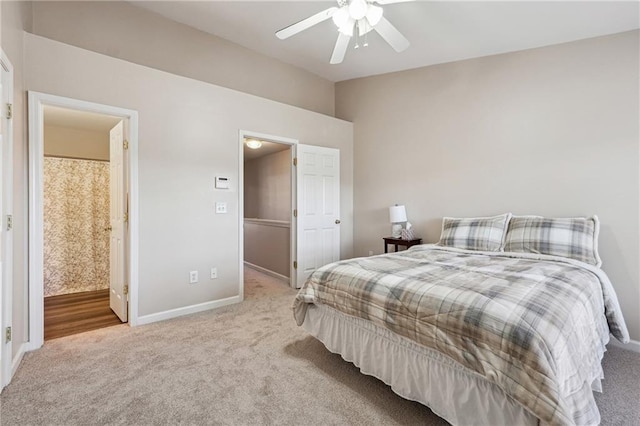 carpeted bedroom with a ceiling fan, ensuite bath, baseboards, and vaulted ceiling
