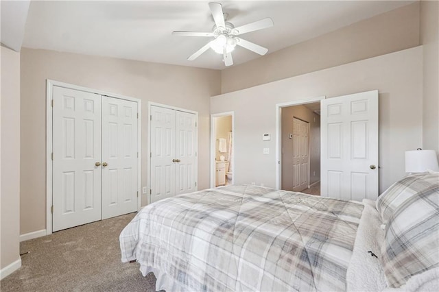 carpeted bedroom featuring baseboards, ceiling fan, vaulted ceiling, and two closets