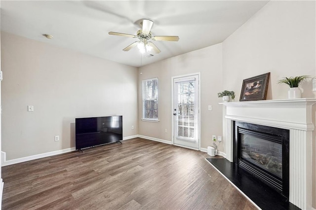 unfurnished living room with baseboards, a fireplace, wood finished floors, and a ceiling fan