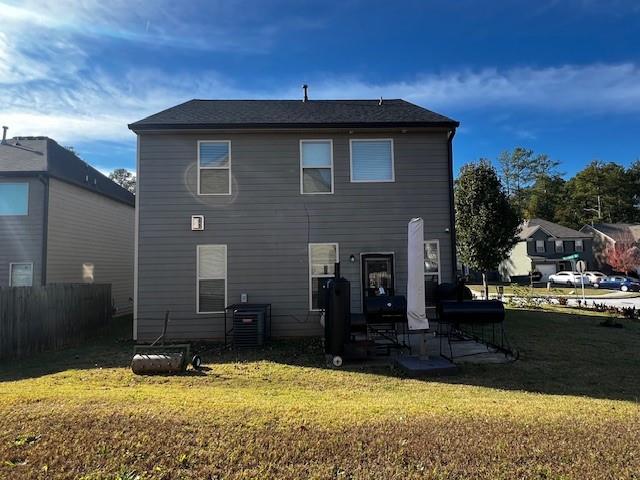 rear view of property featuring a lawn and central AC unit