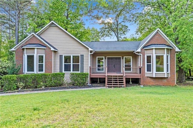 rear view of property with a lawn, a deck, and brick siding