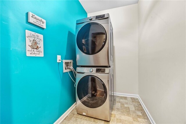 clothes washing area featuring baseboards, laundry area, and stacked washer / dryer
