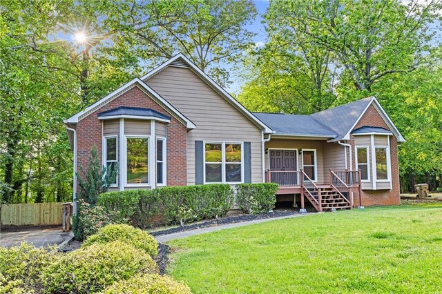rear view of property with a lawn, fence, and brick siding