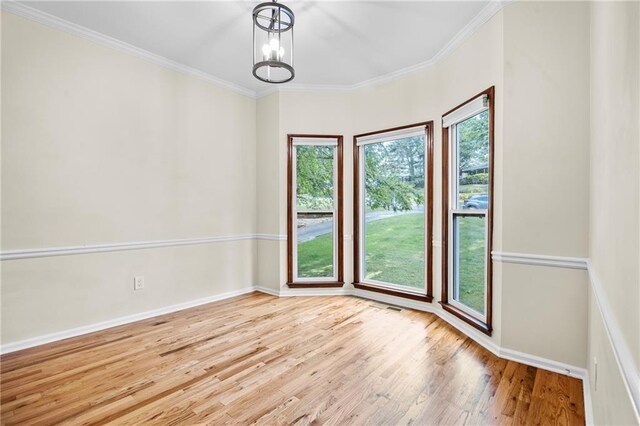 empty room featuring crown molding, baseboards, and wood finished floors