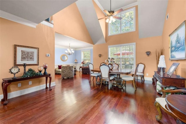 dining space featuring ornamental molding, ceiling fan with notable chandelier, baseboards, a towering ceiling, and wood finished floors
